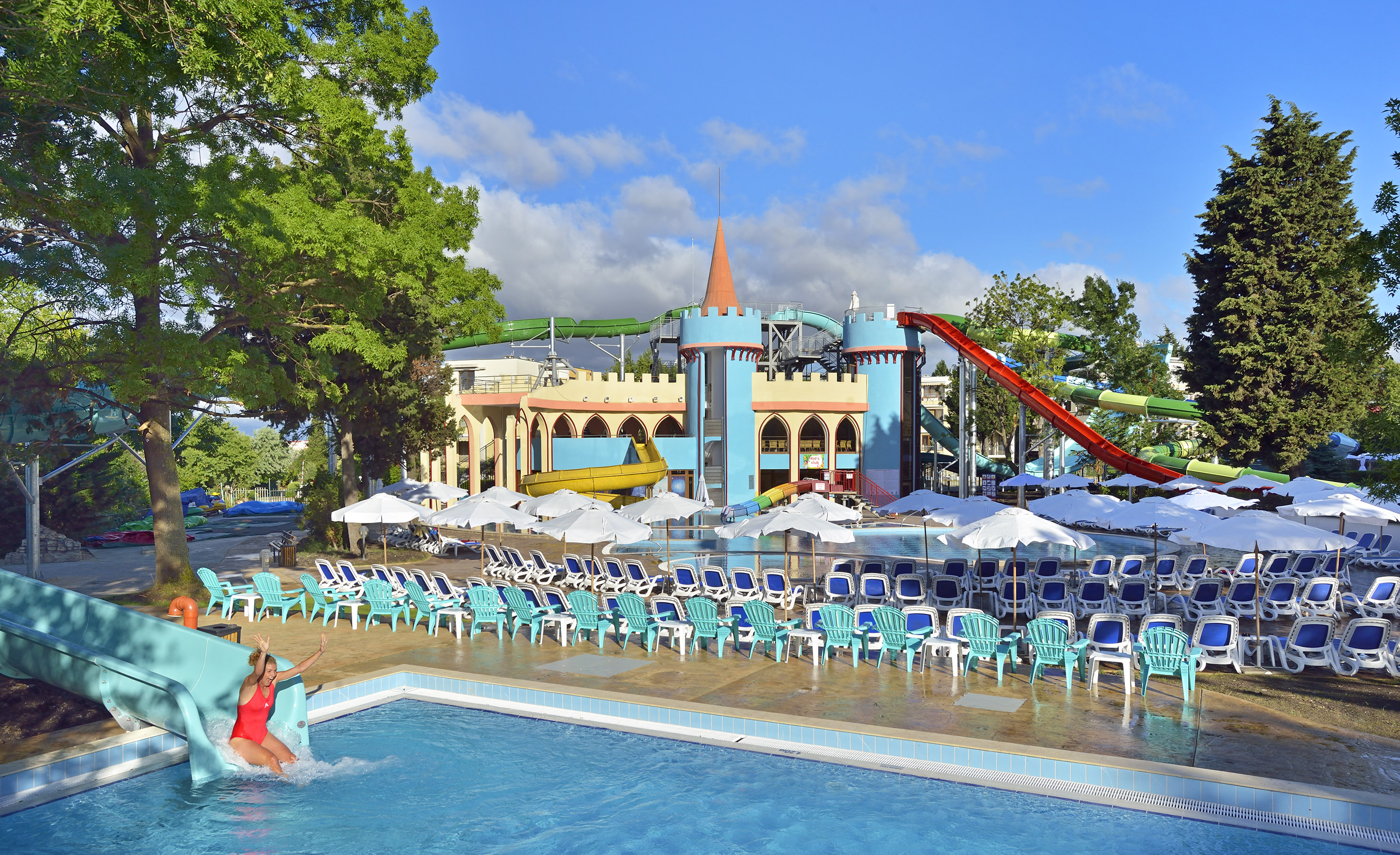 a woman in a pool with chairs and a slide