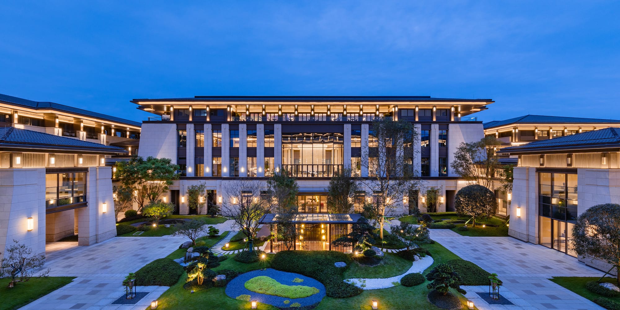 a large building with a garden and trees