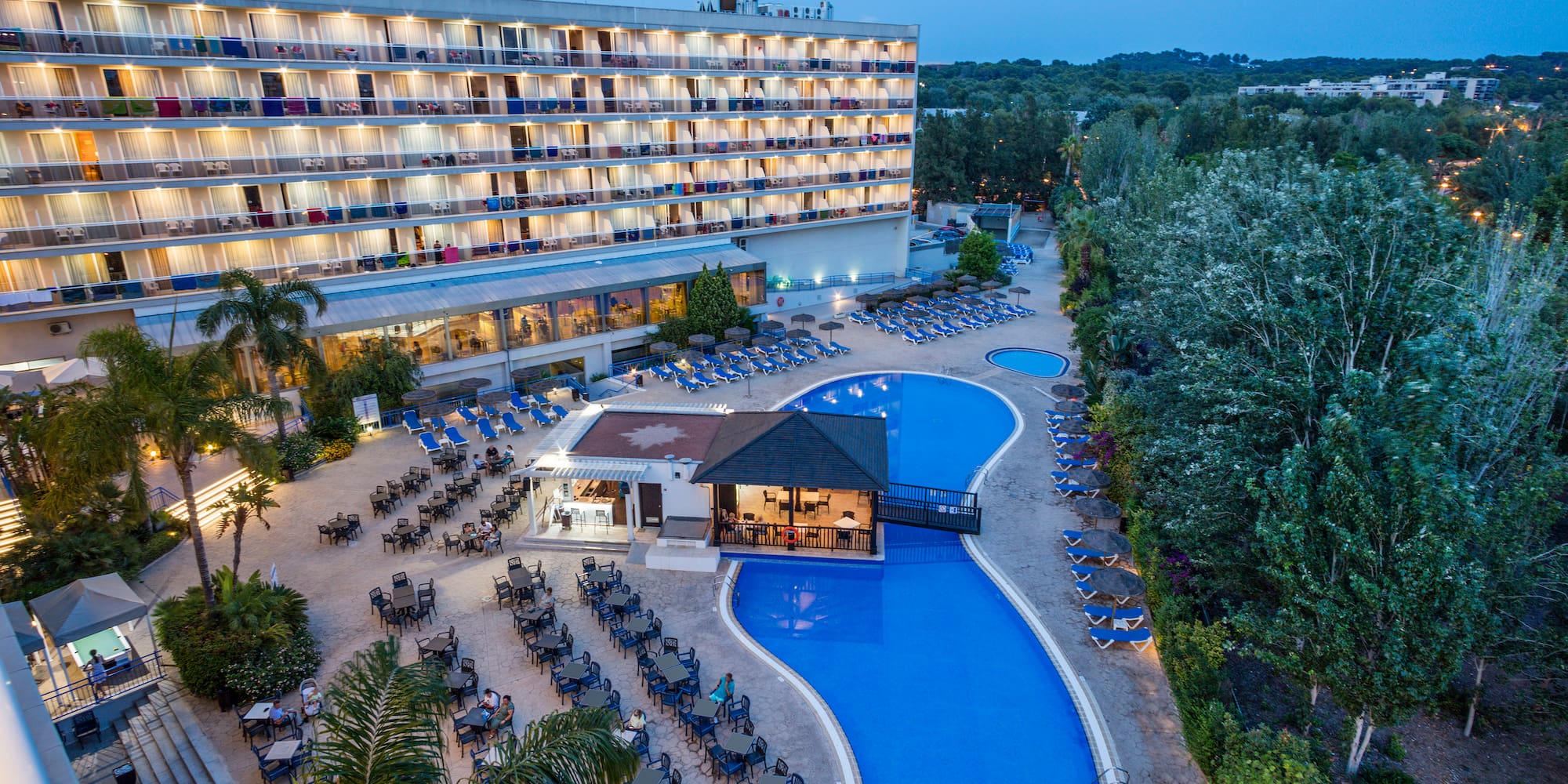 a pool and a building with chairs and trees