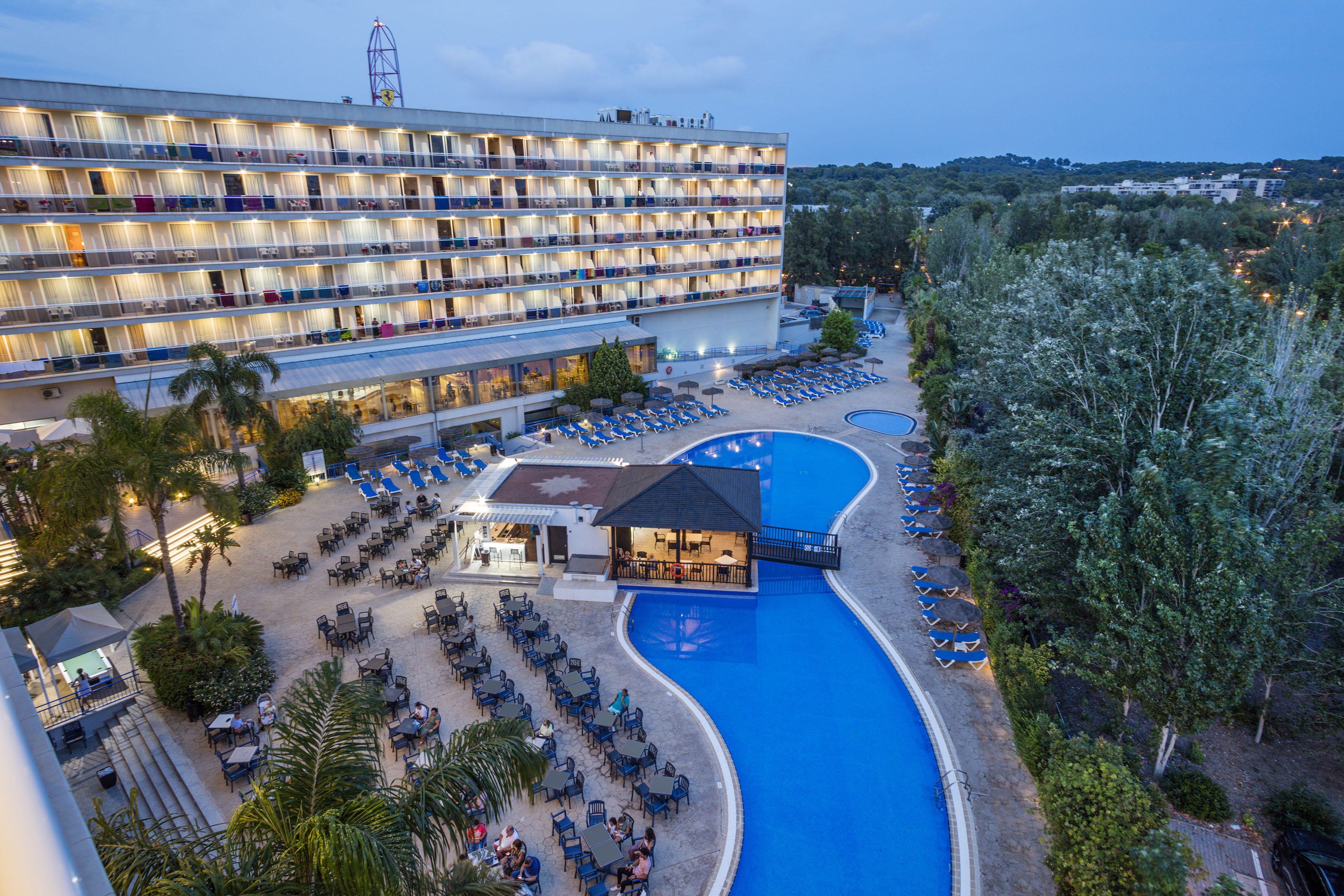 a pool and a building with chairs and trees