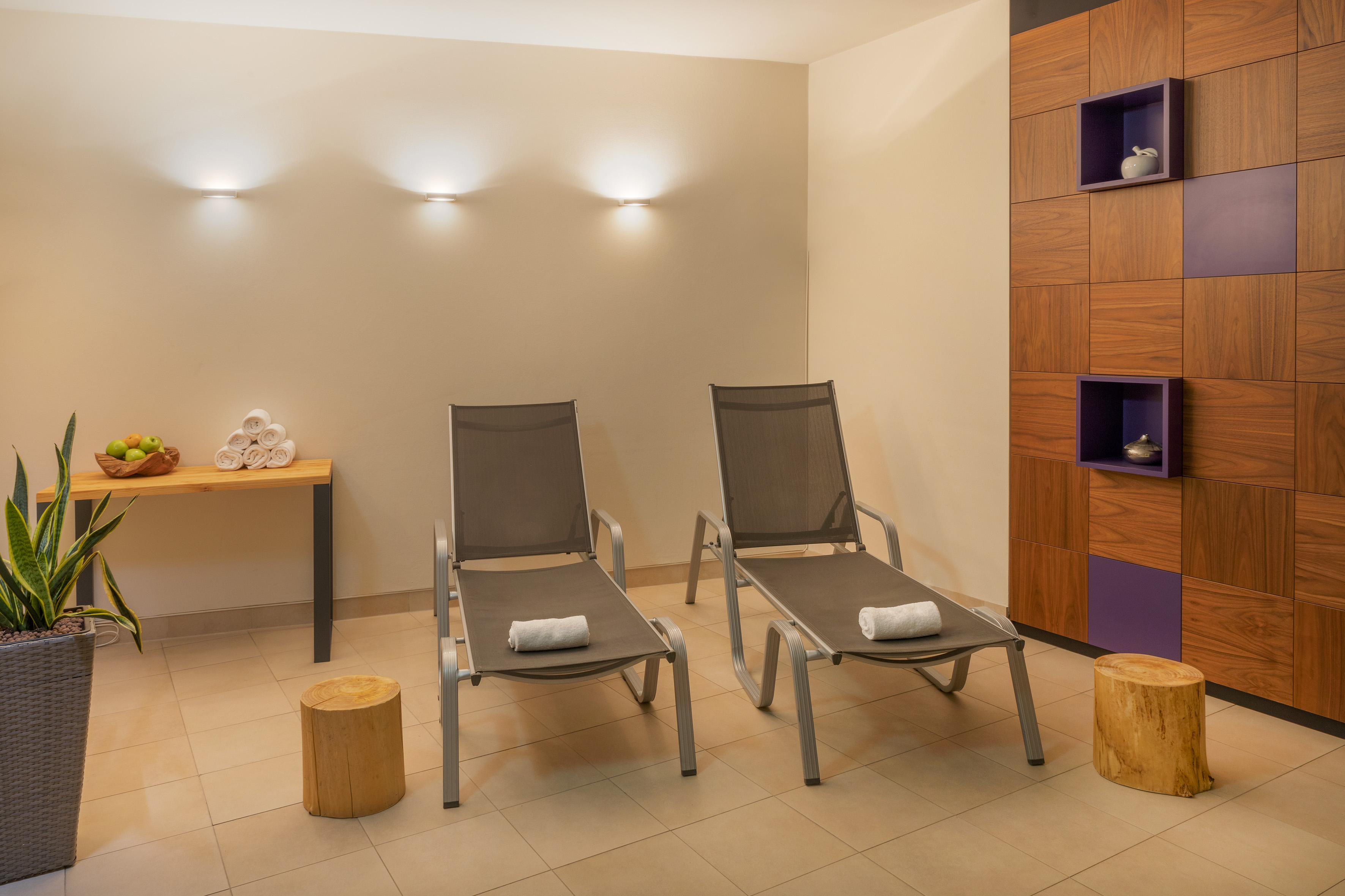 Relaxation lounge with two modern spa loungers, fresh towels, and wood details.