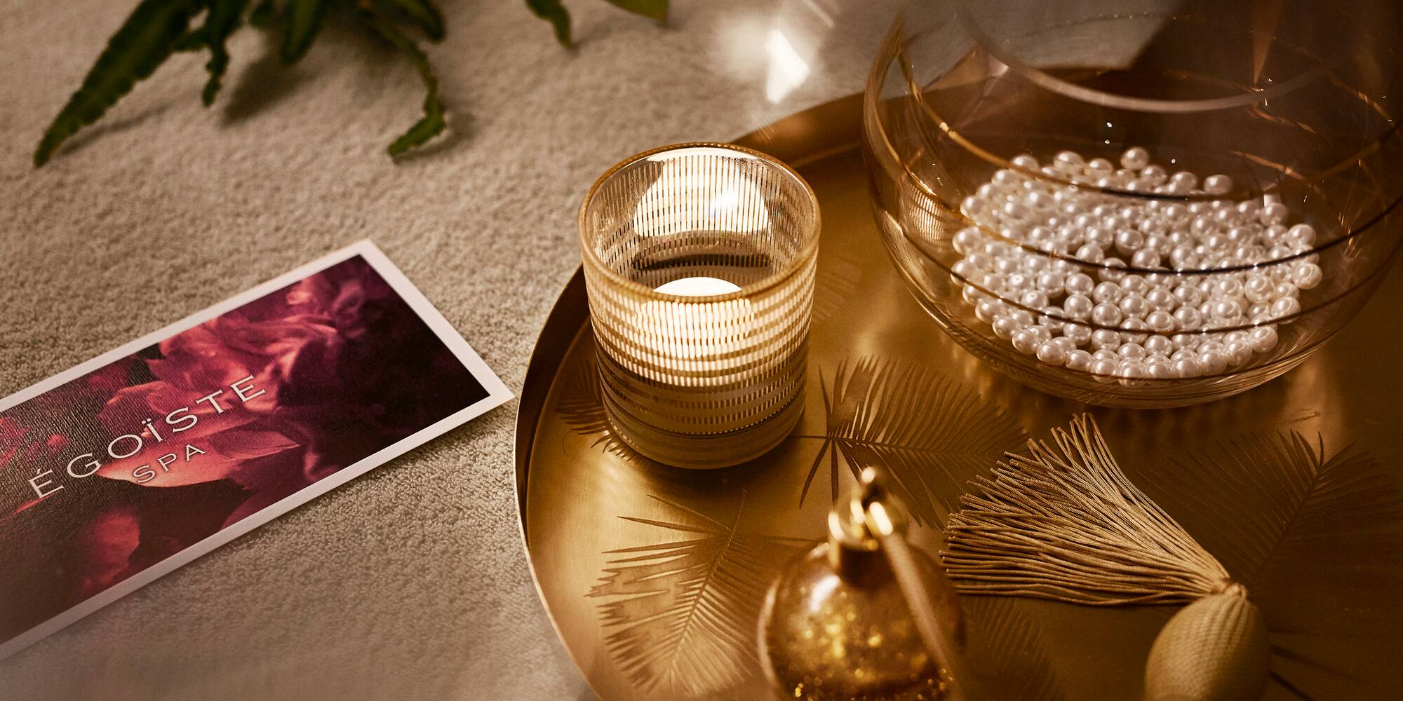 a tray with a candle and pearls on it
