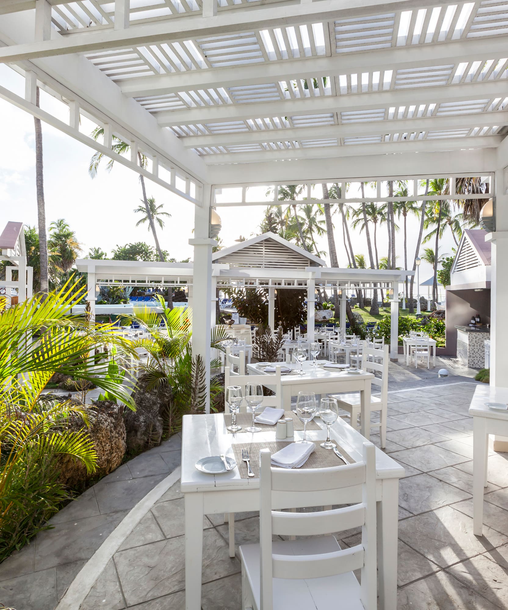 a white outdoor dining area with tables and chairs