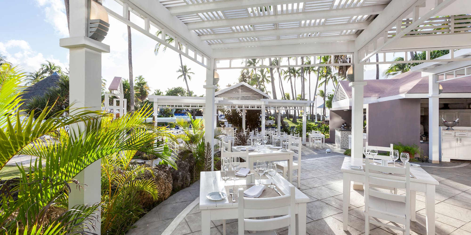 a white outdoor dining area with tables and chairs