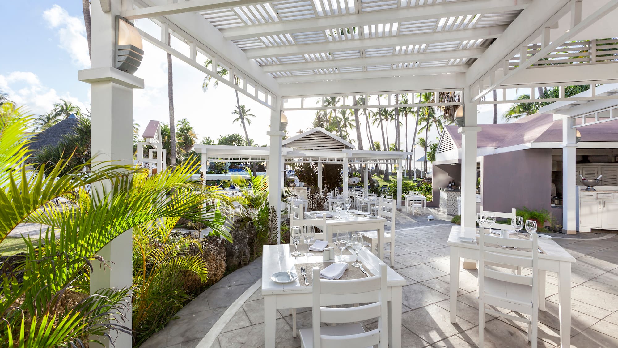 a white outdoor dining area with tables and chairs