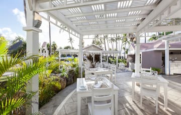 a white outdoor dining area with tables and chairs