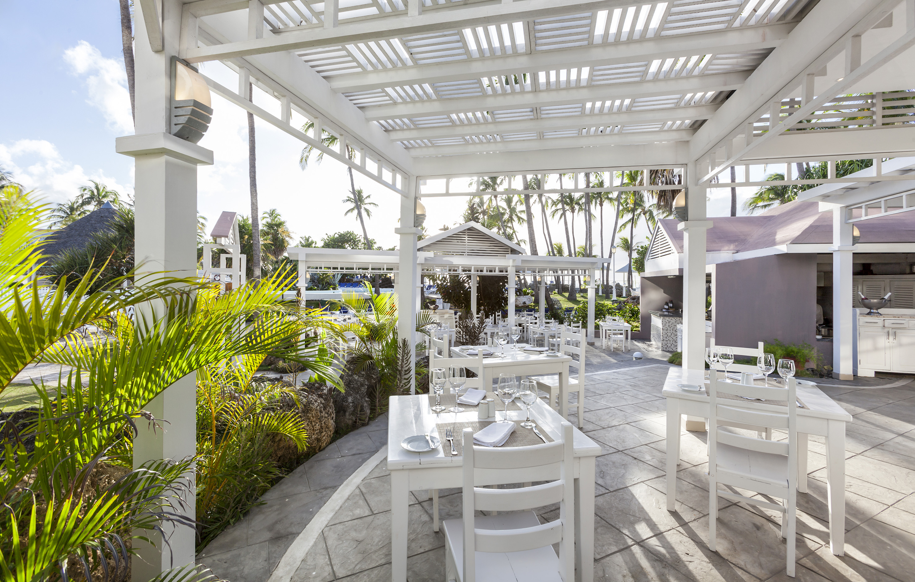a white outdoor dining area with tables and chairs