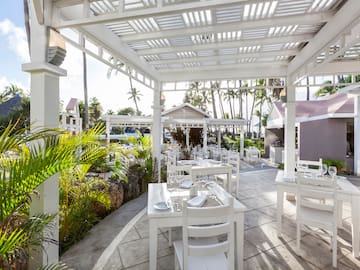 a white outdoor dining area with tables and chairs