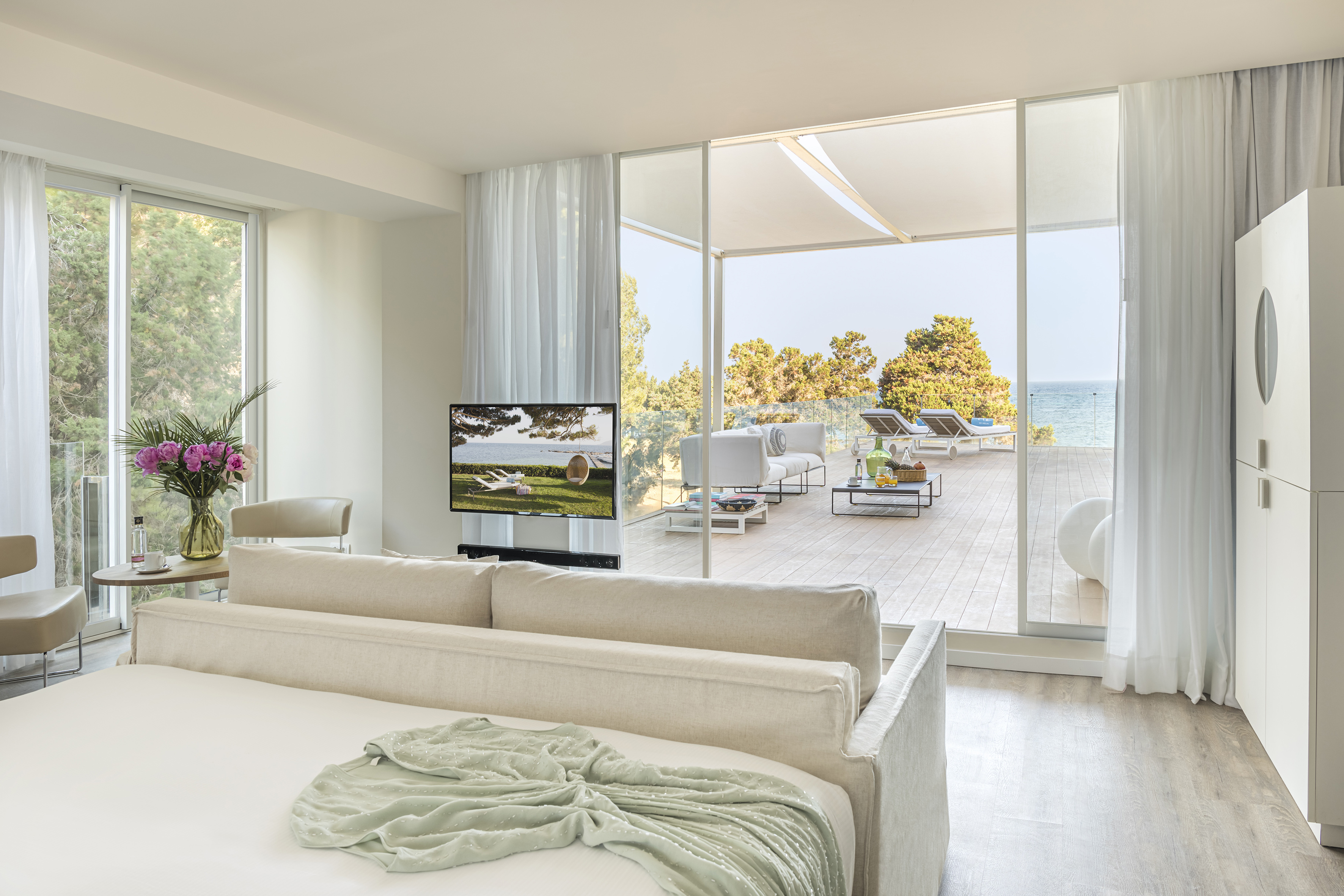 Luxury coastal hotel suite with ocean view terrace and modern bedroom.