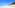 White sand beach with turquoise ocean, blue sky, and tropical trees.