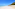 White sand beach with turquoise ocean, blue sky, and tropical trees.