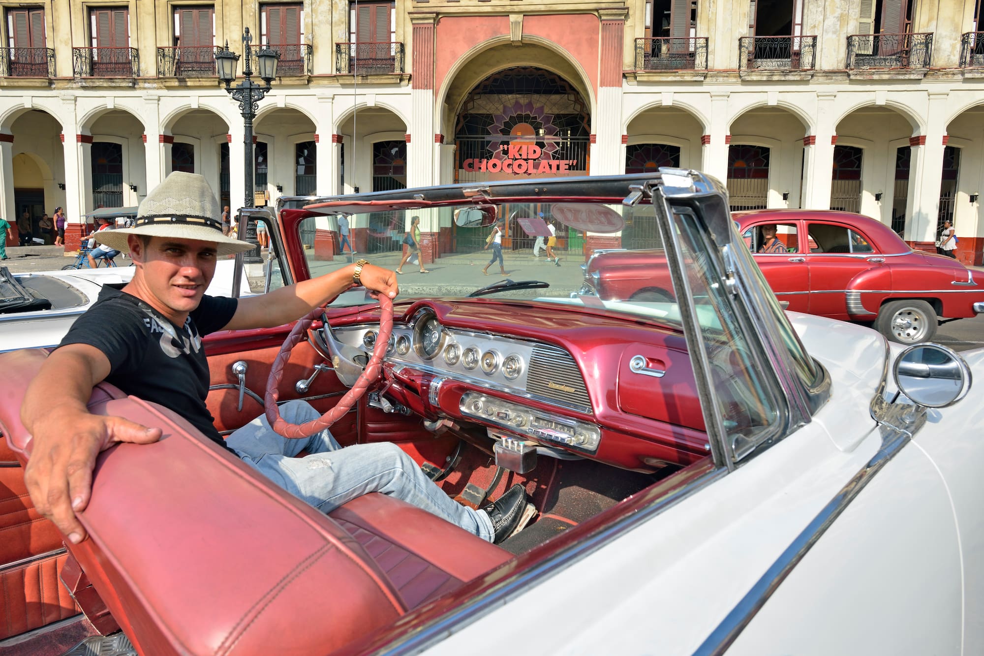 a man in a hat sitting in a convertible car
