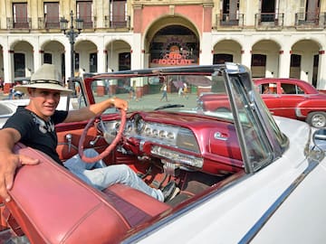 a man in a hat sitting in a convertible car