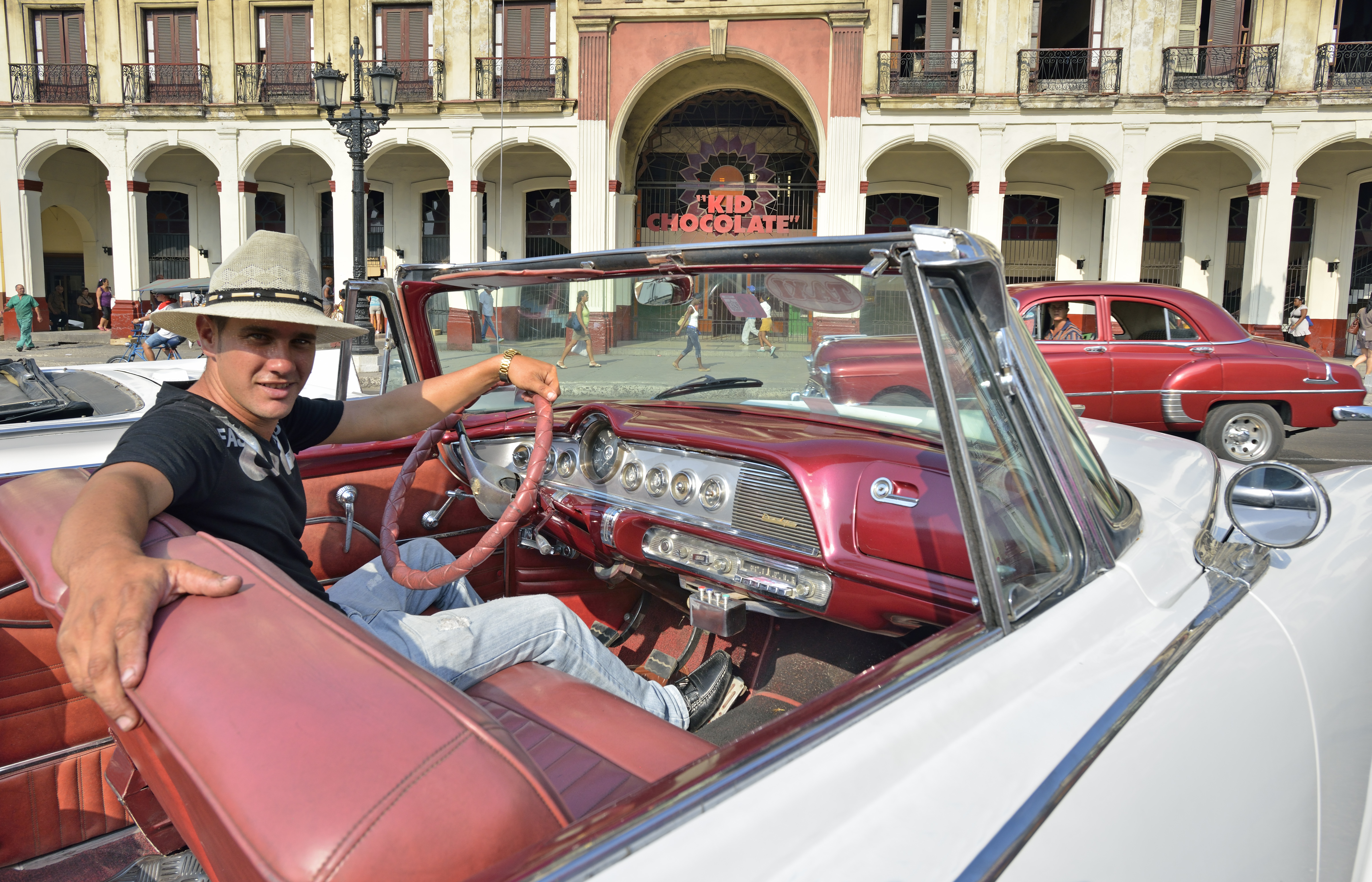a man in a hat sitting in a convertible car
