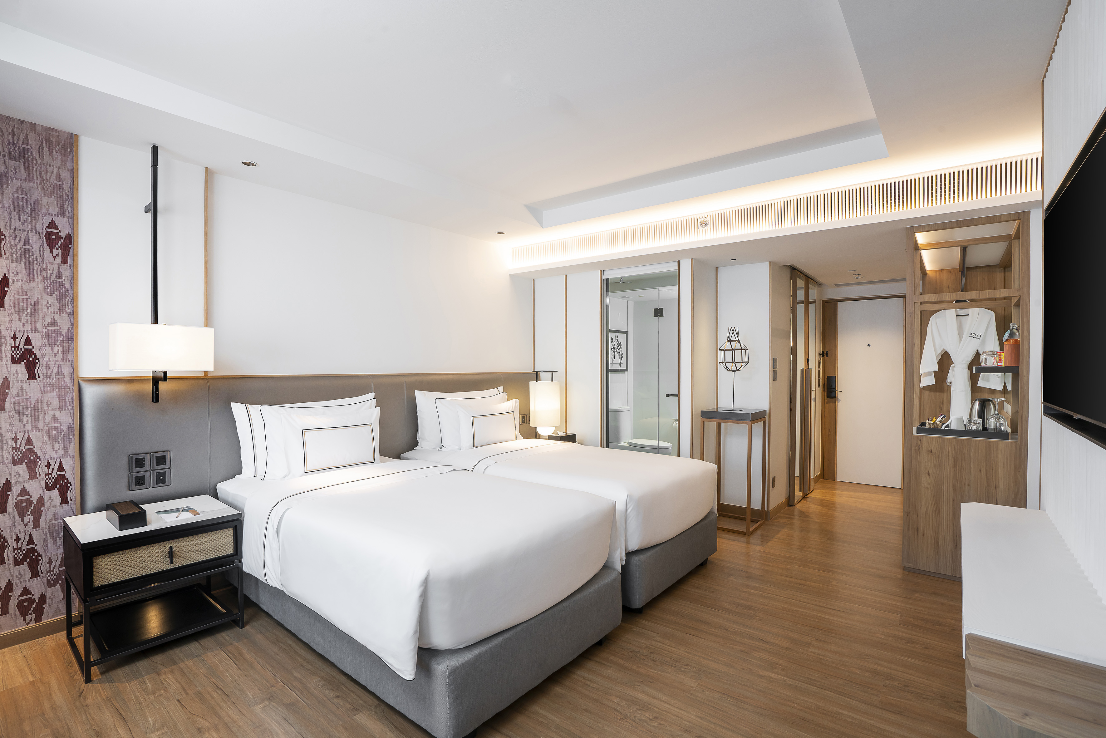 Modern hotel room with two twin beds, hardwood floor, and contemporary decor.