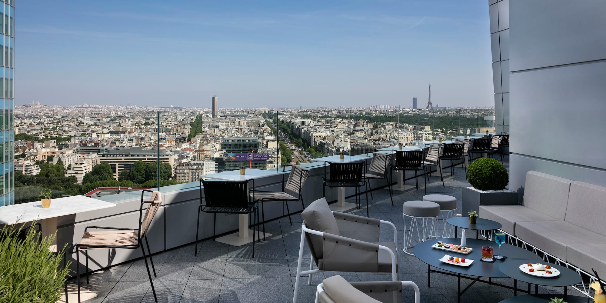 Paris rooftop bar with Eiffel Tower view and modern outdoor lounge seating.