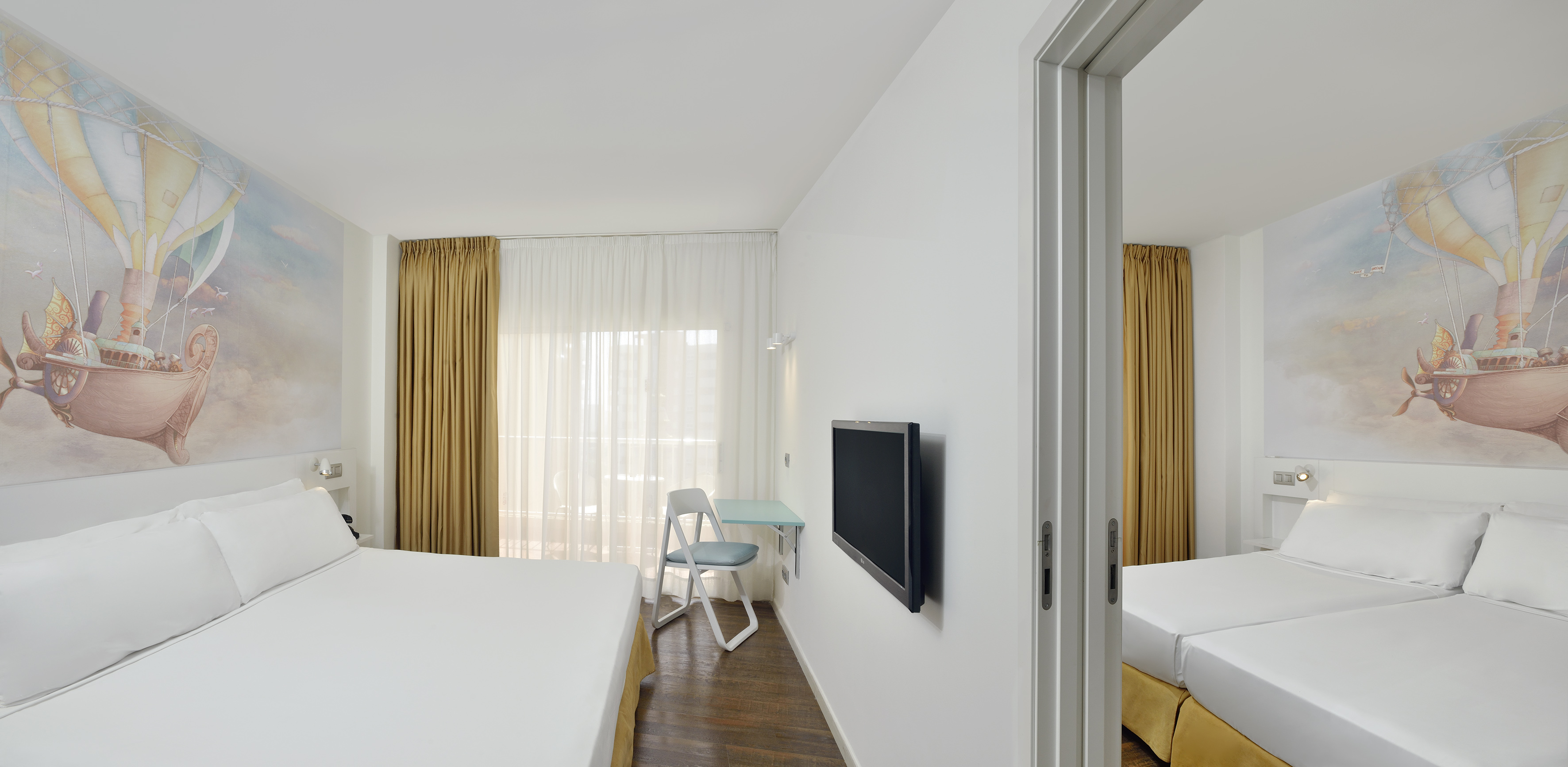 Modern family hotel room with hot air balloon mural, double and twin beds.