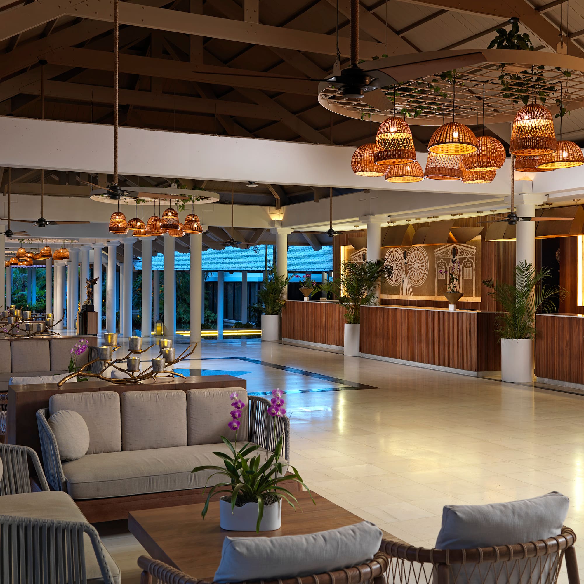 Luxury hotel lobby with tropical decor, comfortable seating, and rattan lighting.