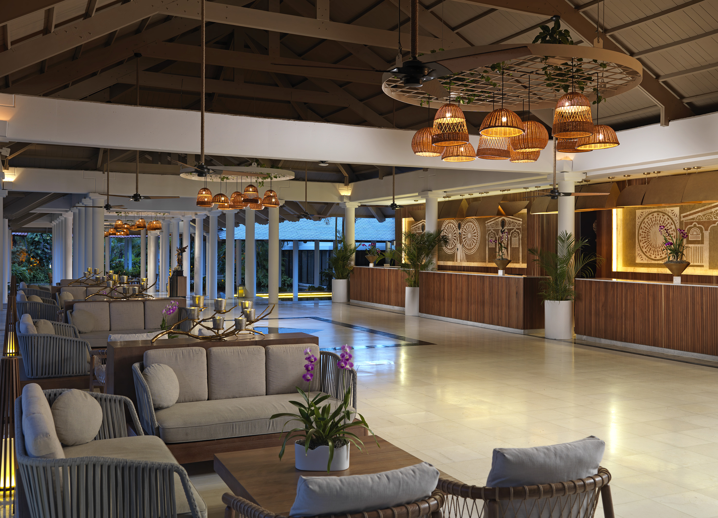 Luxury hotel lobby with tropical decor, comfortable seating, and rattan lighting.