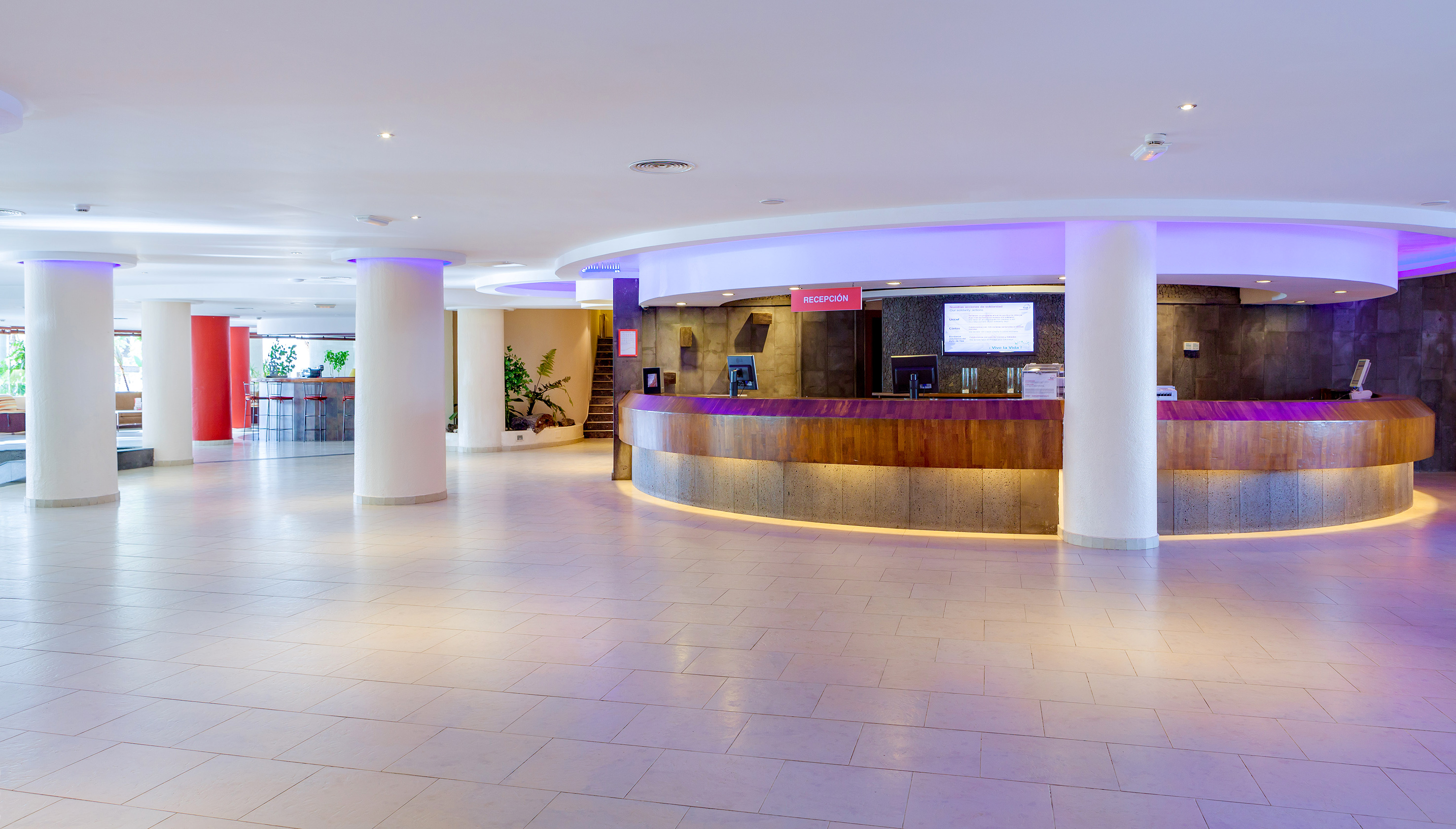 Modern hotel reception desk with purple accent lighting in a spacious lobby. - SOL Lanzarote All Inclusive, Lanzarote