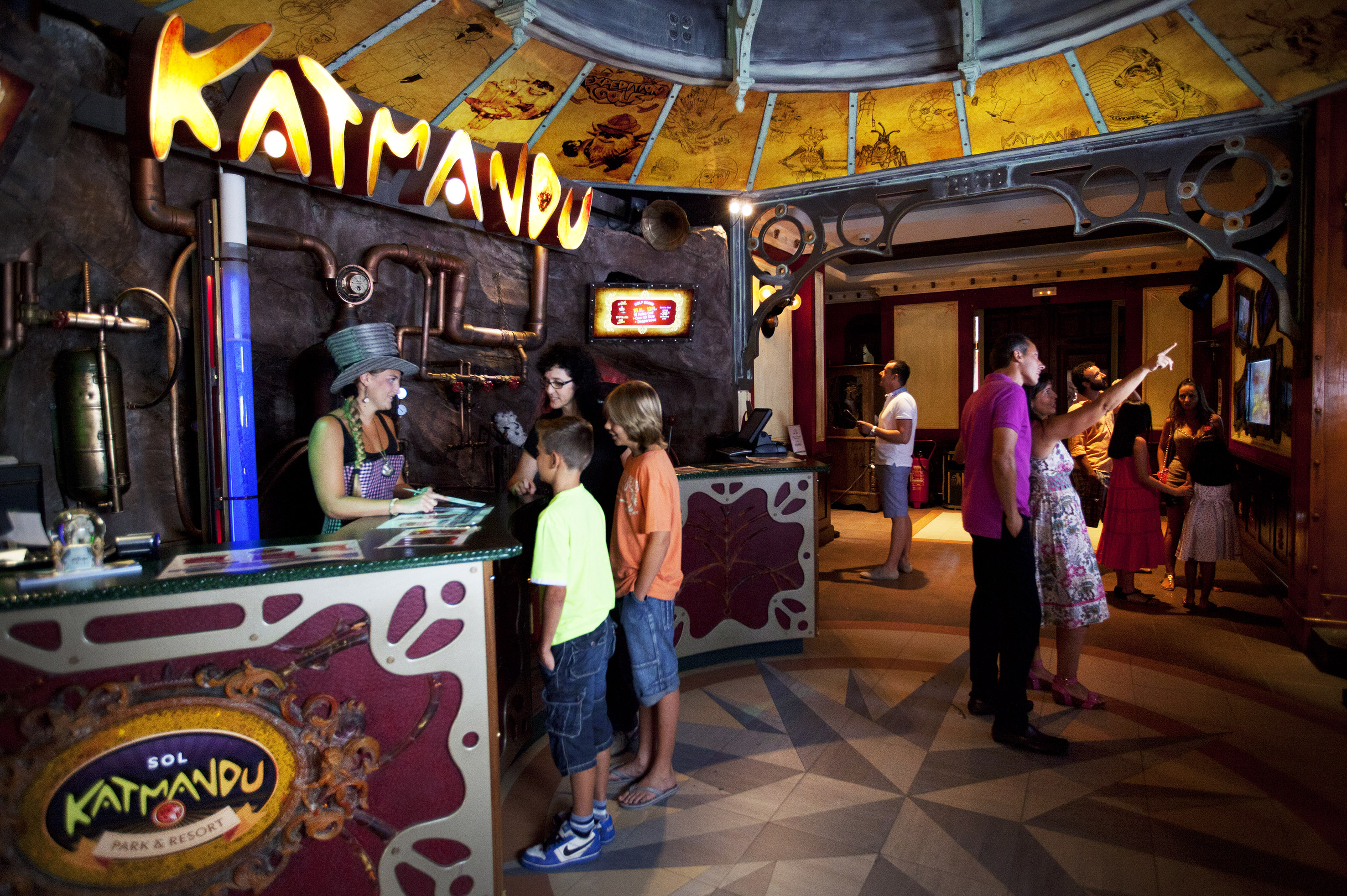 Sol Katmandu Park reception with staff assisting family and themed adventure decor.
