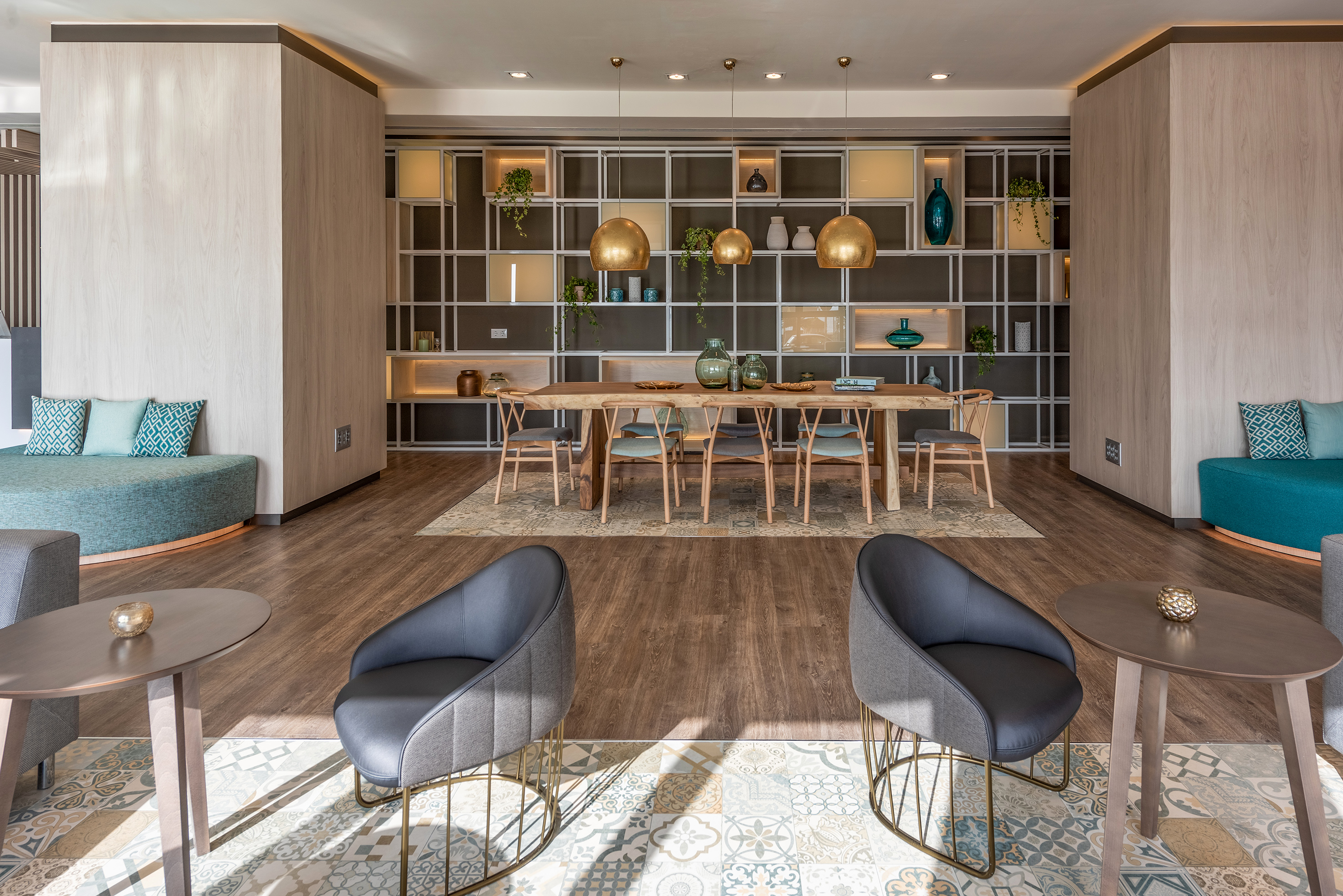 Modern dining and lounge with wooden table, decorative shelving, and stylish seating.