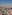 Vista aérea de Barcelona con Torre Glòries, Sagrada Familia y Montjuïc bajo cielo azul.