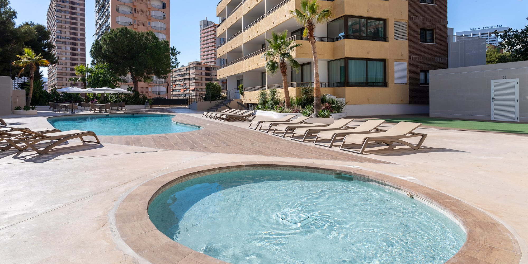 a pool with lounge chairs and a building