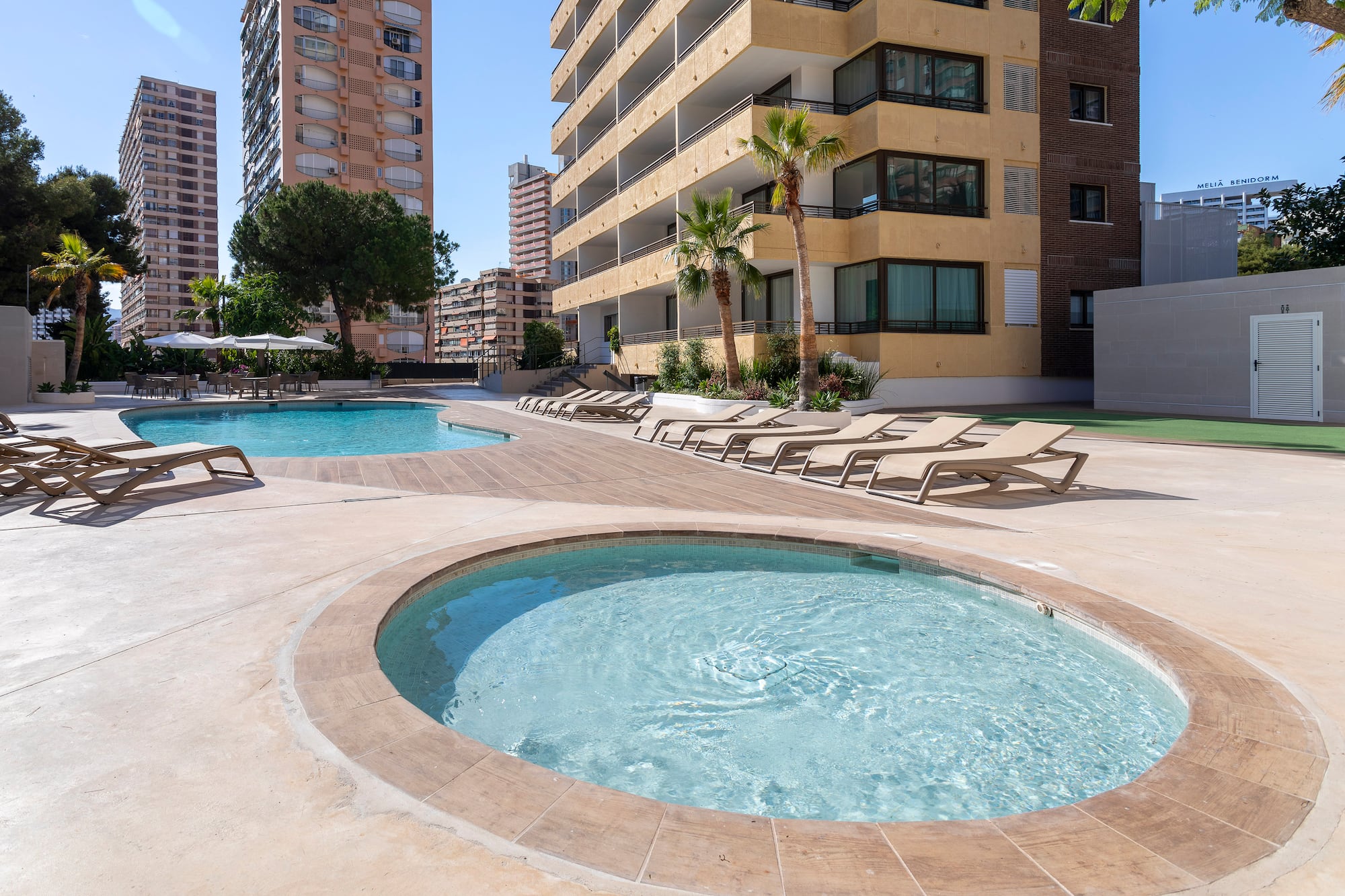 a pool with lounge chairs and a building