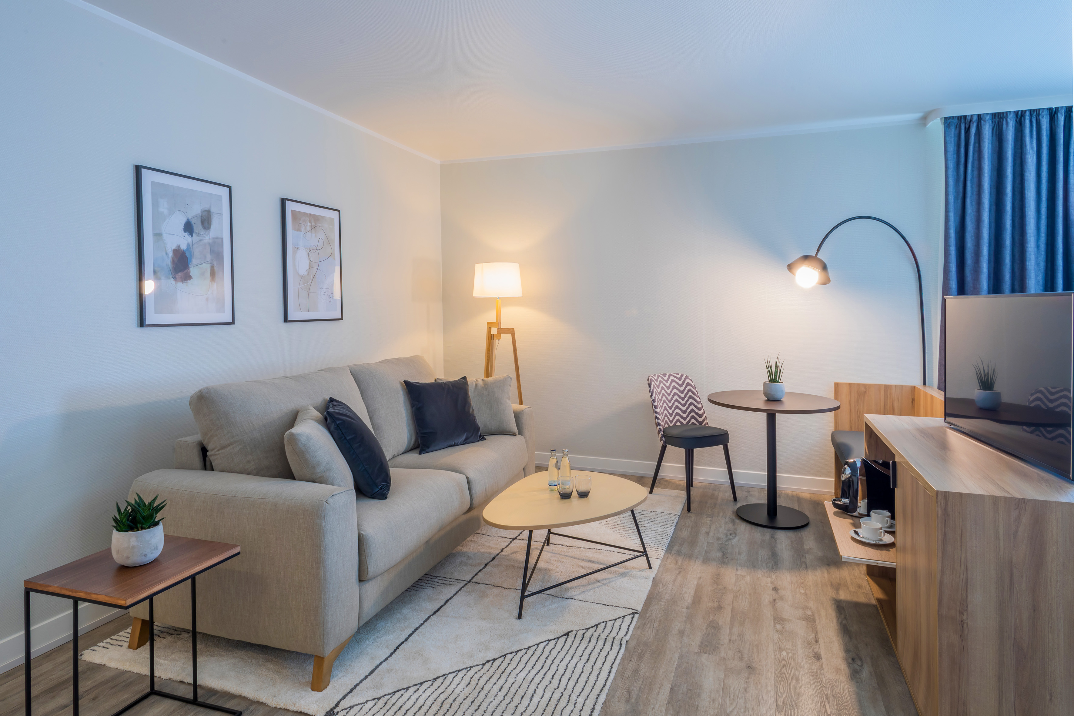 Contemporary living room with light sofa, coffee table, arc lamp, and dining nook.