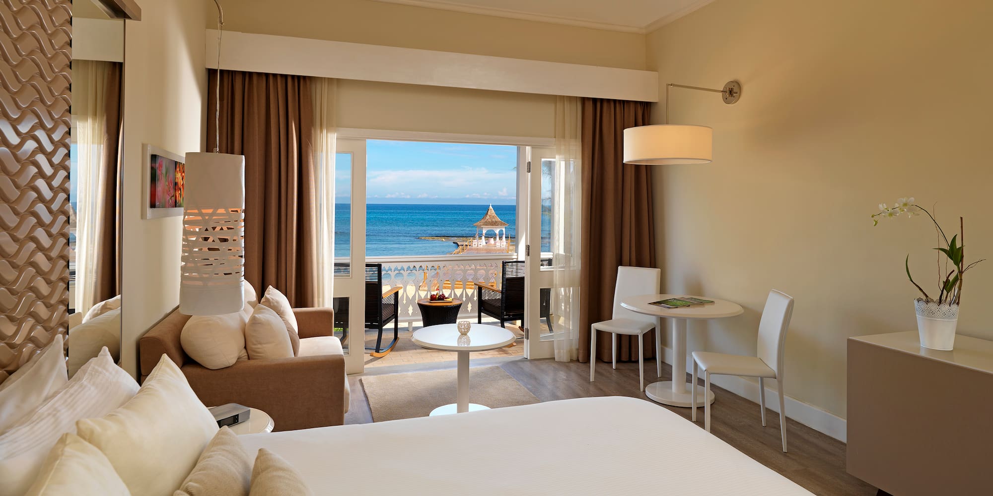 a room with a bed and a table and chairs and a beach view