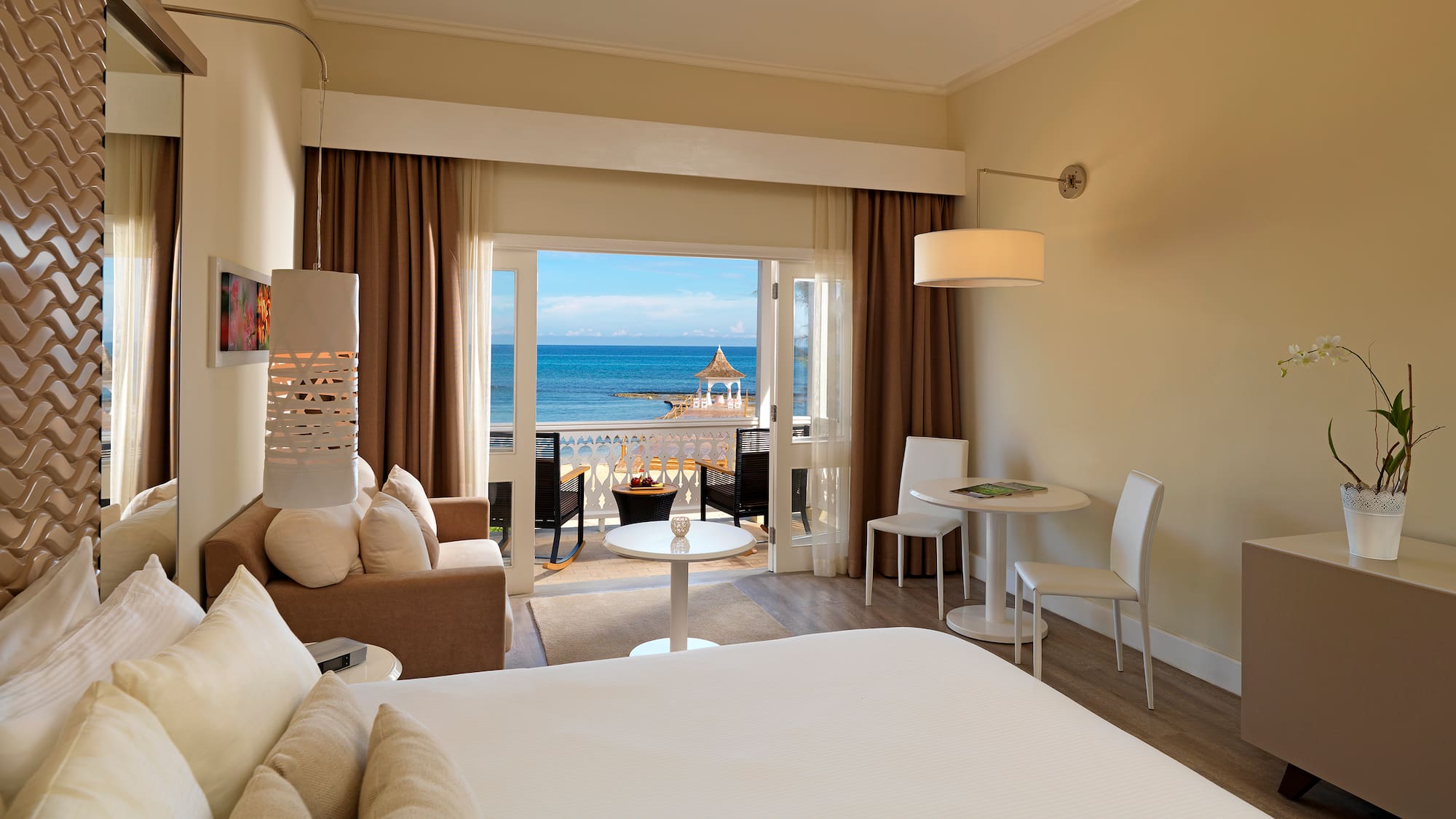 a room with a bed and a table and chairs and a beach view