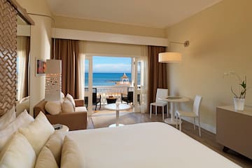 a room with a bed and a table and chairs and a beach view