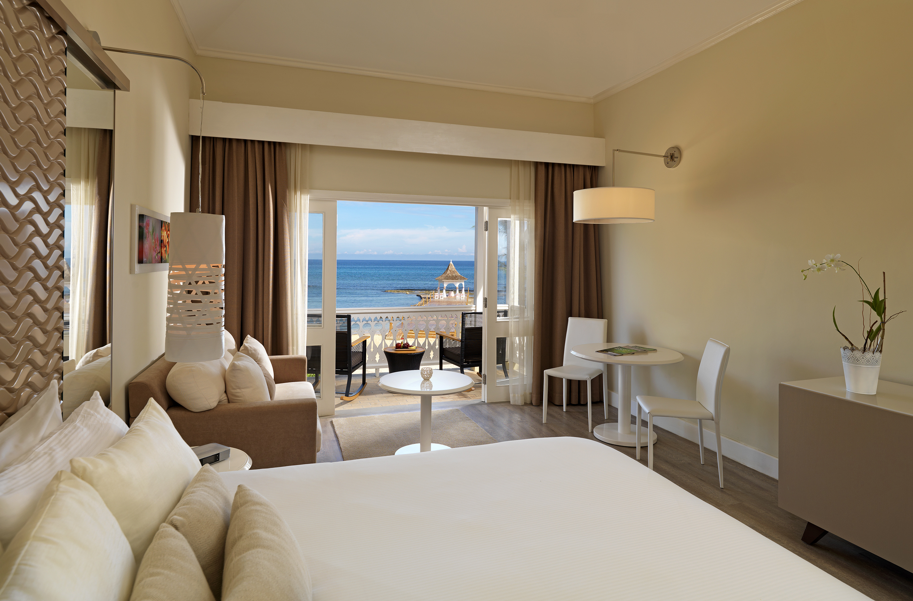 a room with a bed and a table and chairs and a beach view