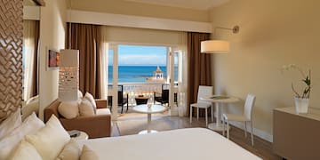 a room with a bed and a table and chairs and a beach view