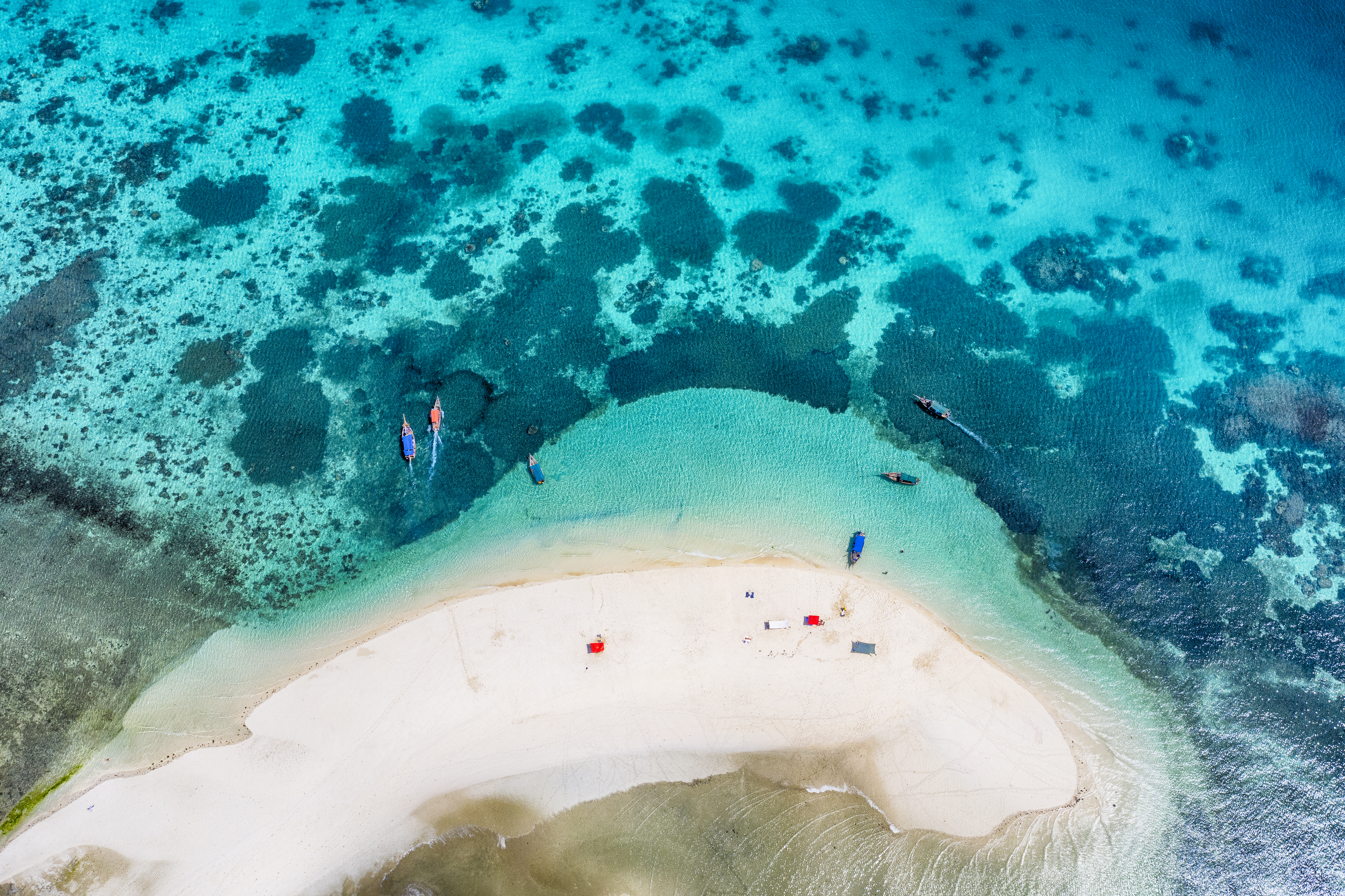 a beach with boats and a sandy island