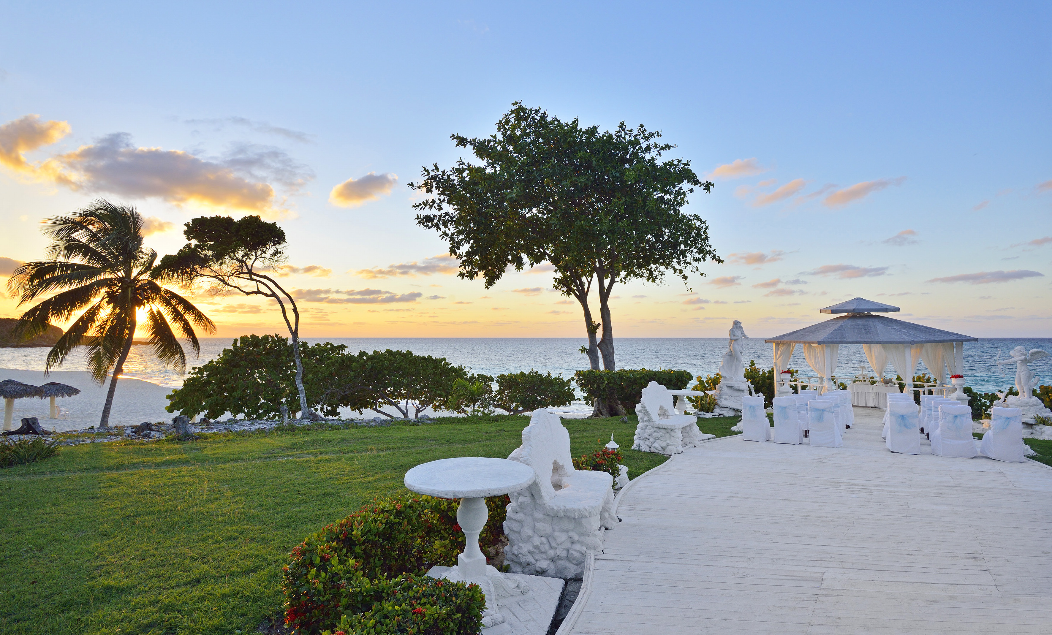 a white patio with a gazebo and trees and a sunset