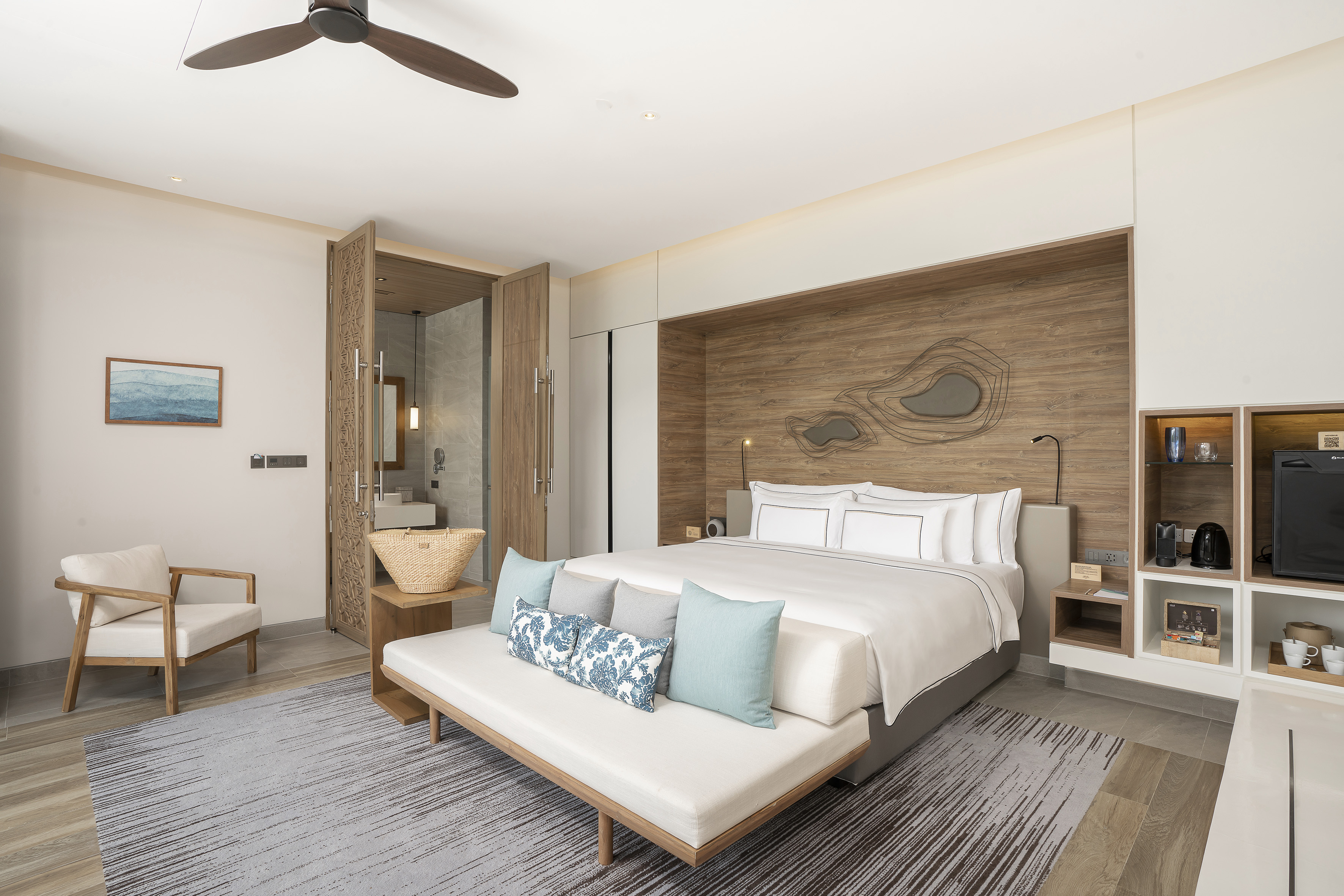 Modern luxury hotel bedroom with king bed, wood accents, and sleek design.