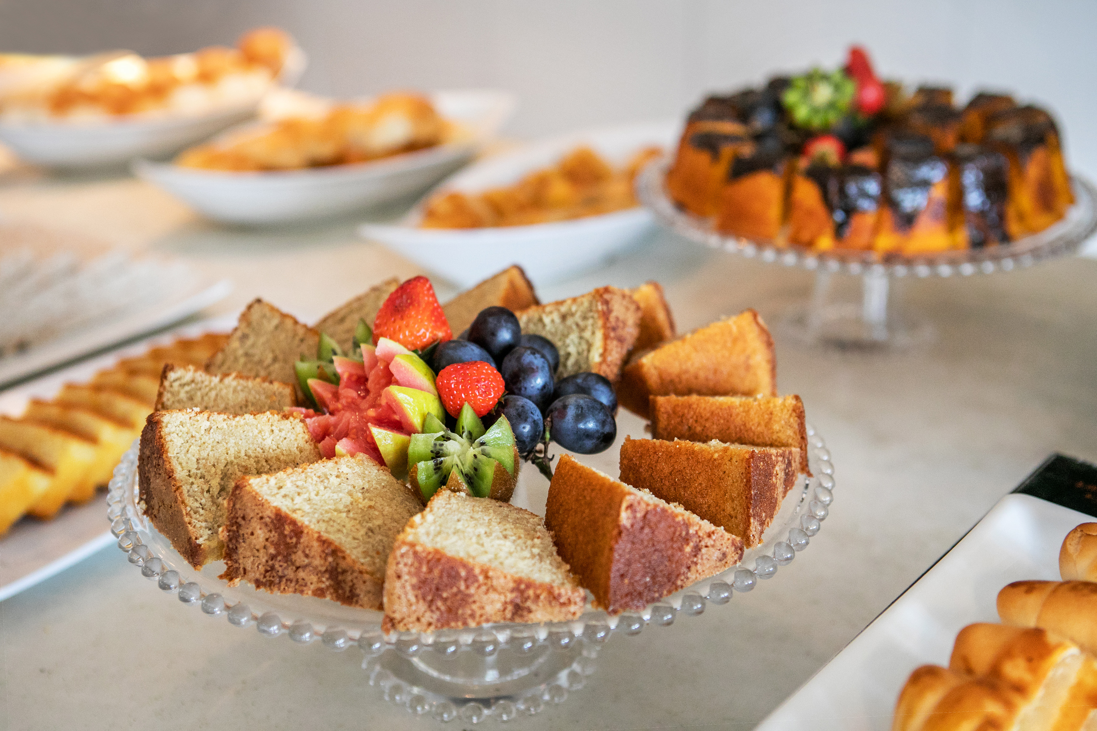 Breakfast buffet: sliced cake, fresh fruit platter, and other baked goods.