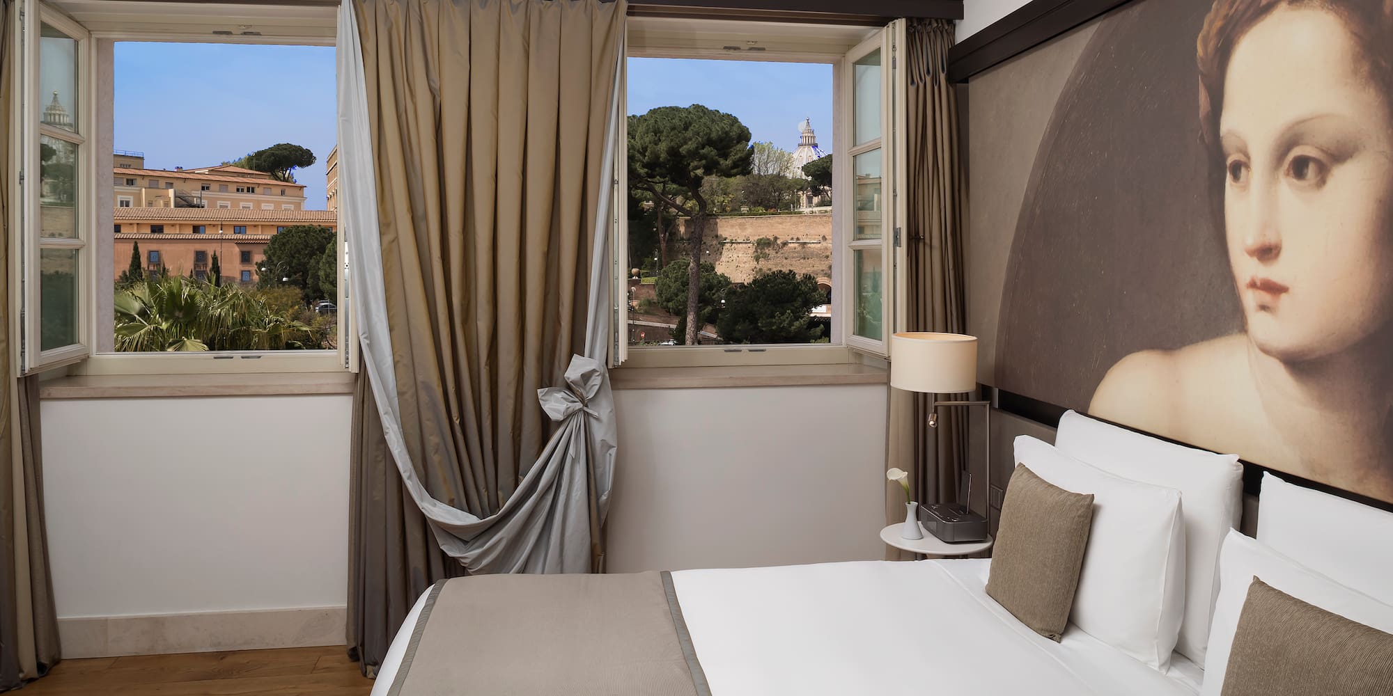 a bed with a lamp and curtains in a room with a view of a city