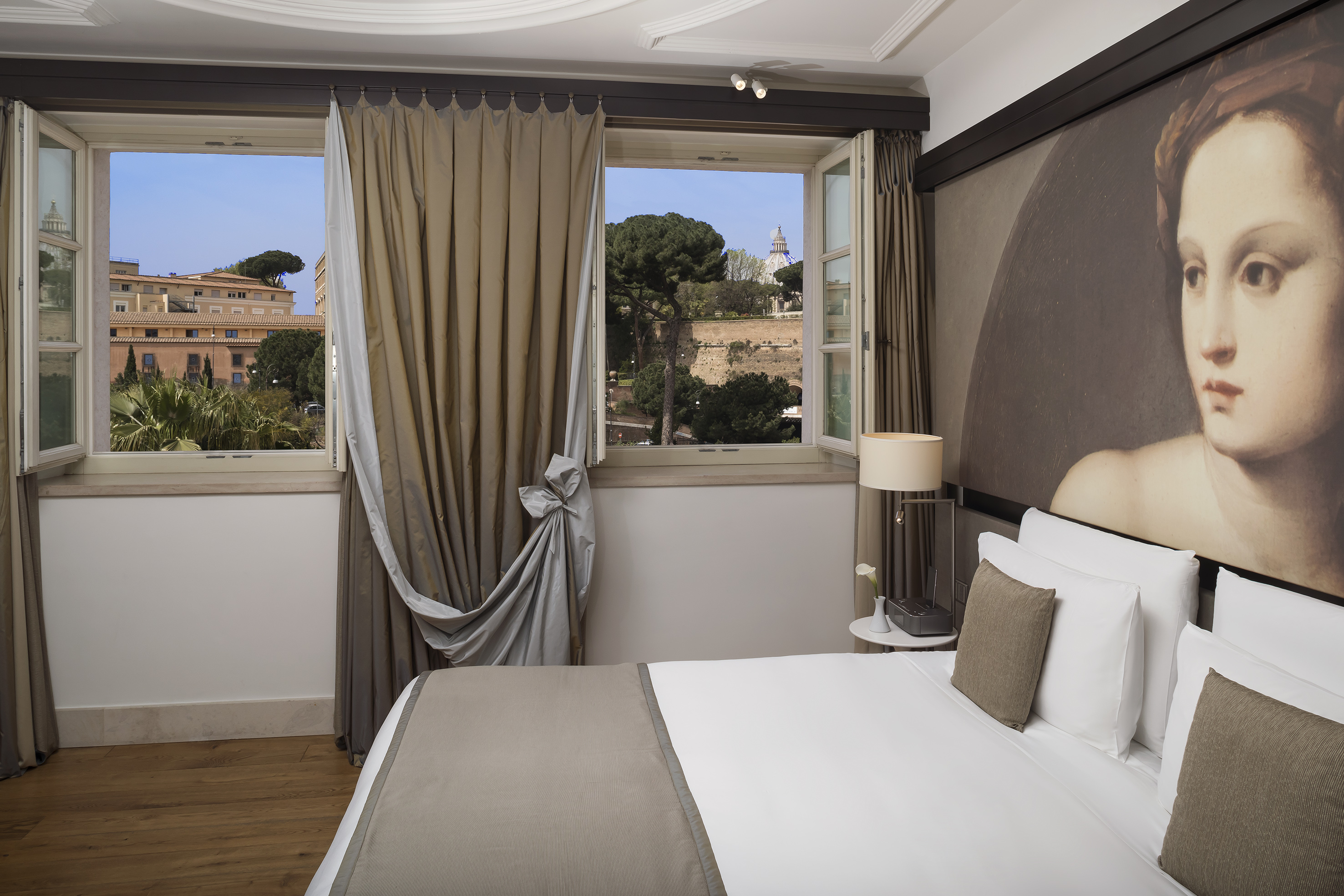 a bed with a lamp and curtains in a room with a view of a city