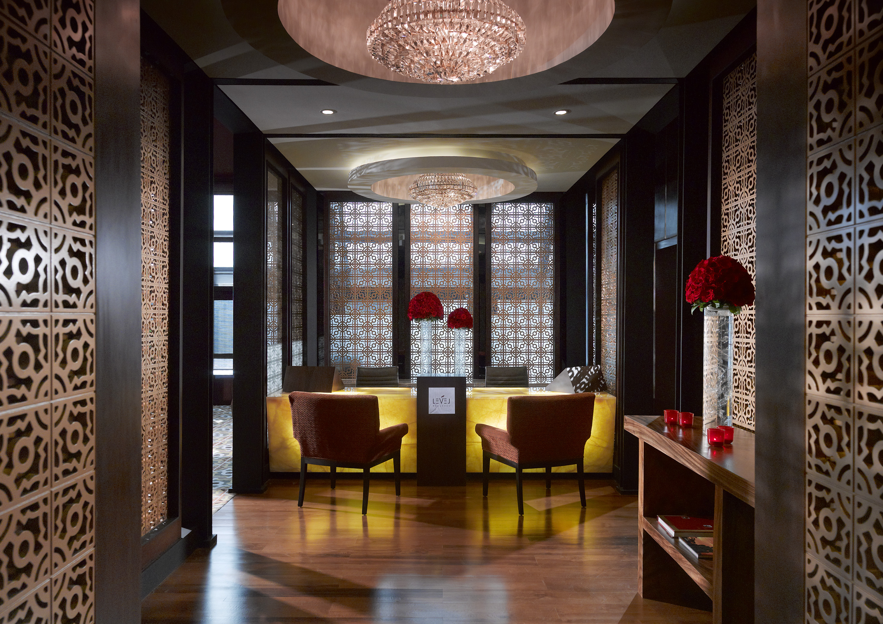 Luxury hotel reception with ornate screens, crystal chandeliers, and bright desk.
