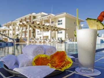 a white towel and a drink on a table next to a pool