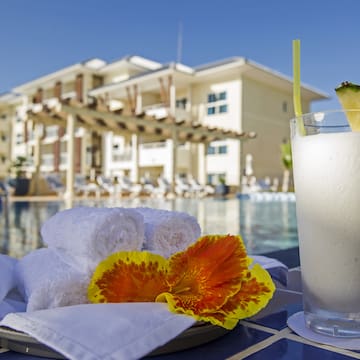 a white towel and a drink on a table next to a pool