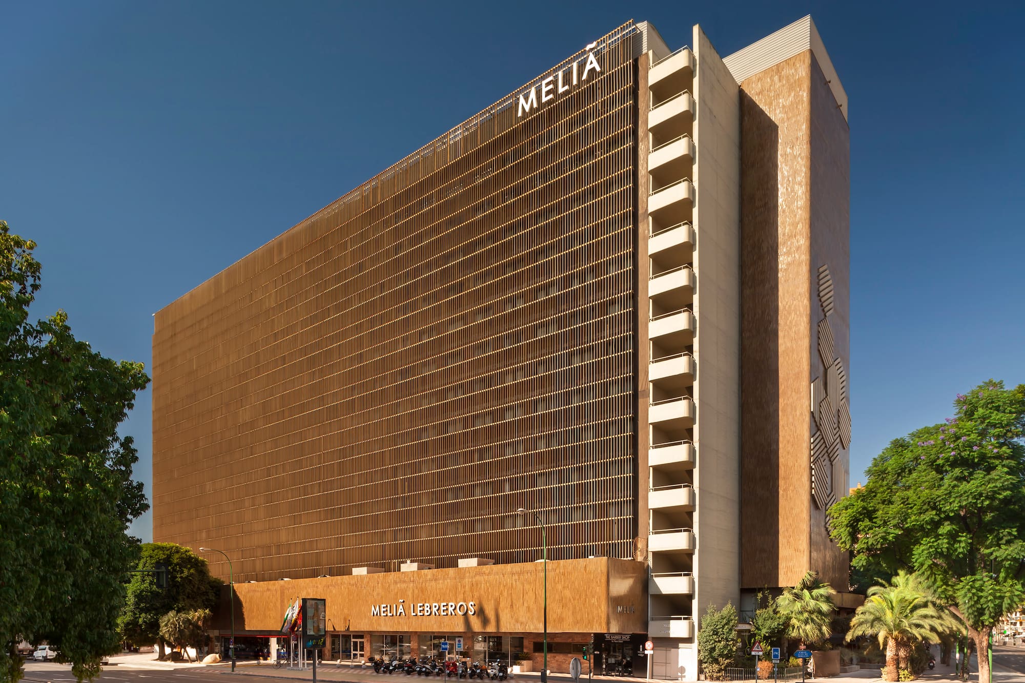 Melia Lebreos hotel building with unique slatted brown facade under blue sky.