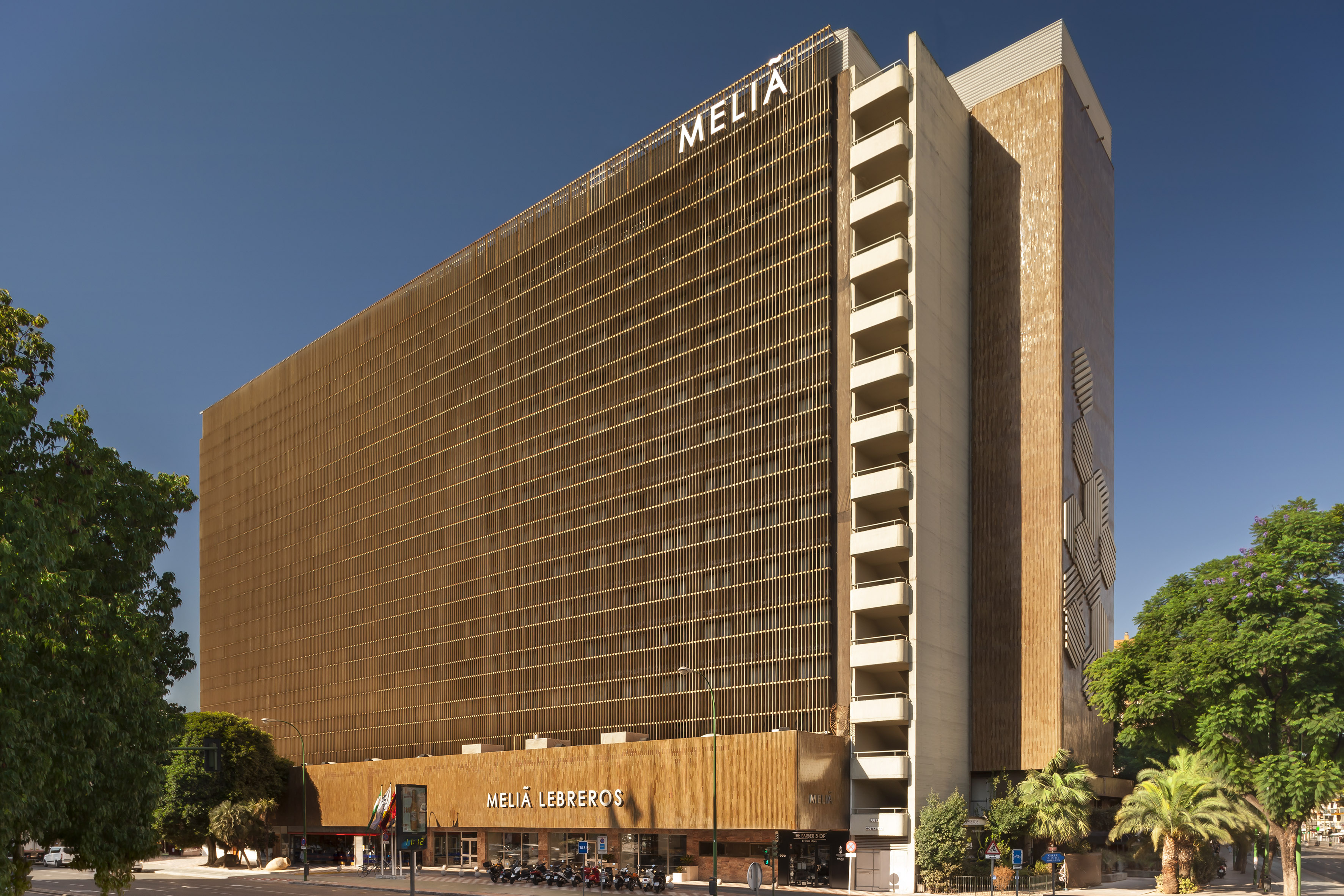 Melia Lebreos hotel building with unique slatted brown facade under blue sky.