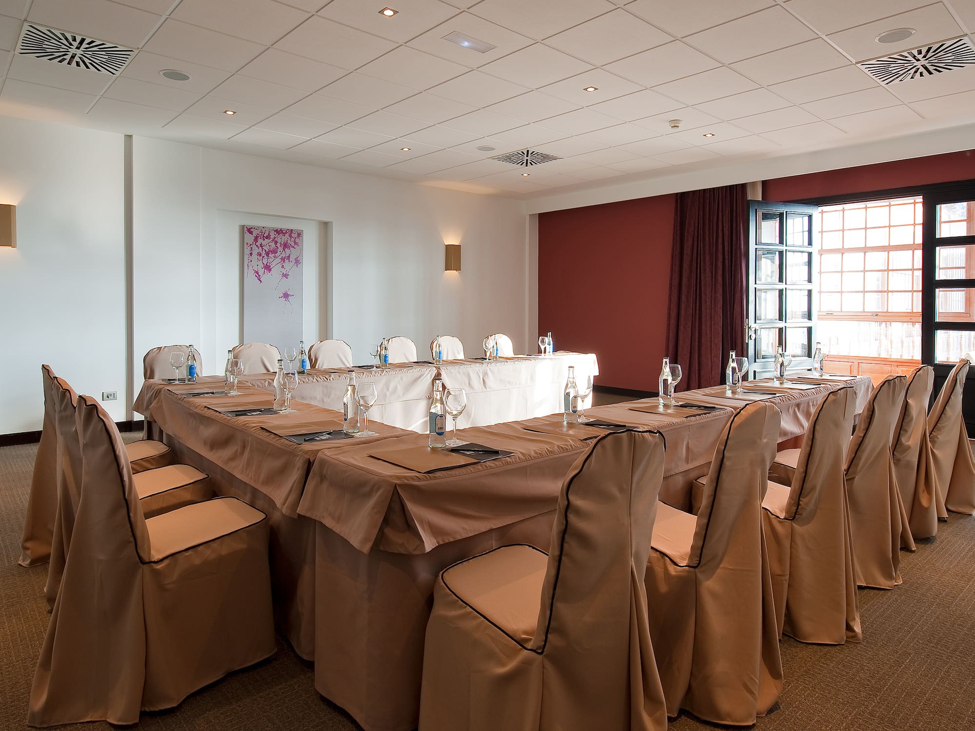 a room with a long table with chairs and glasses