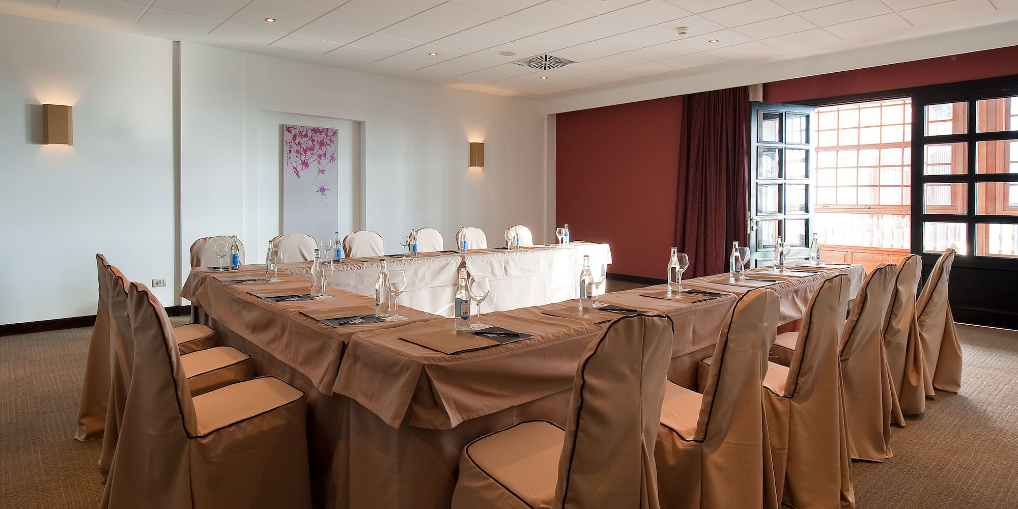 a room with a long table with chairs and glasses