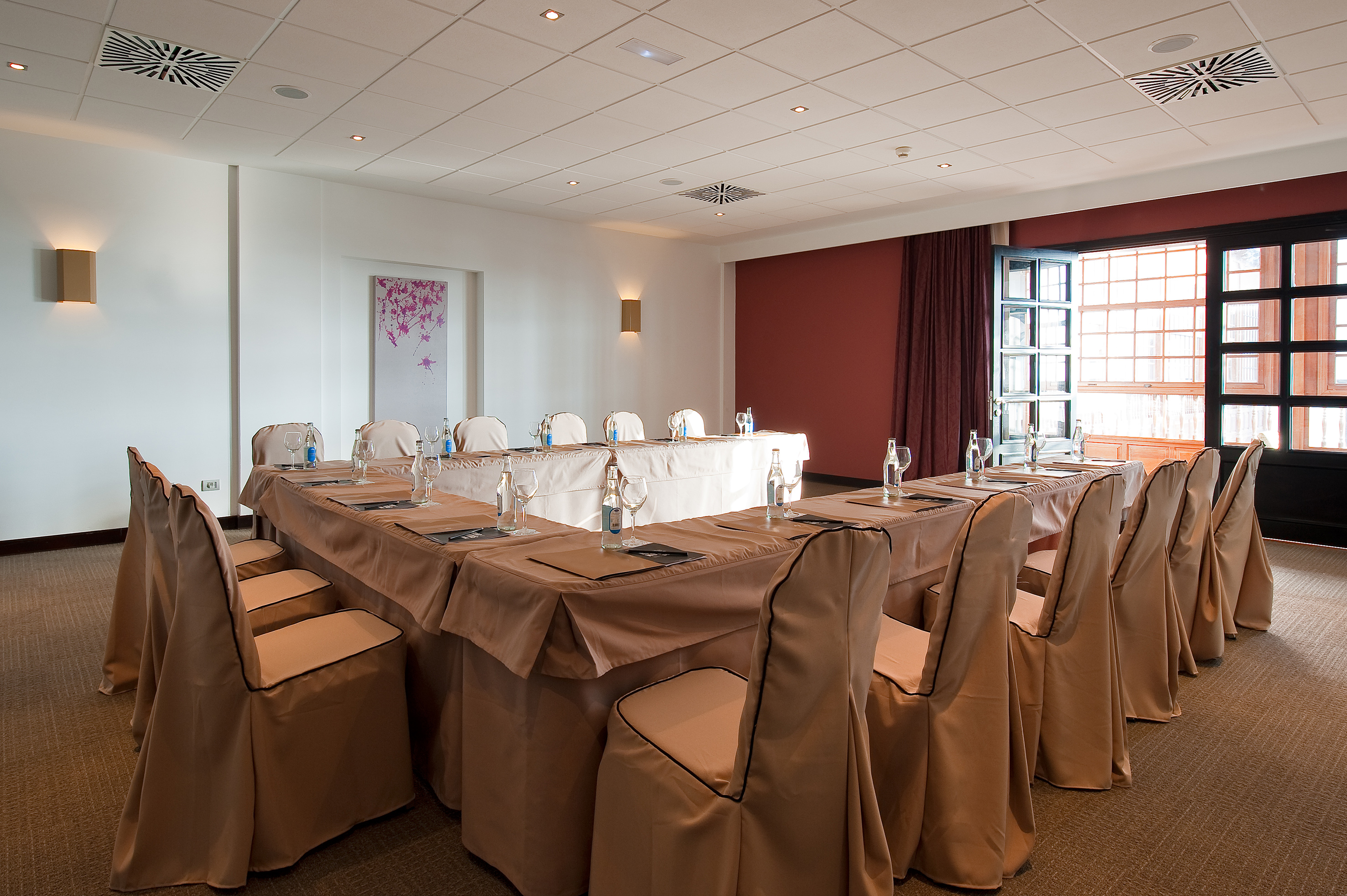 a room with a long table with chairs and glasses