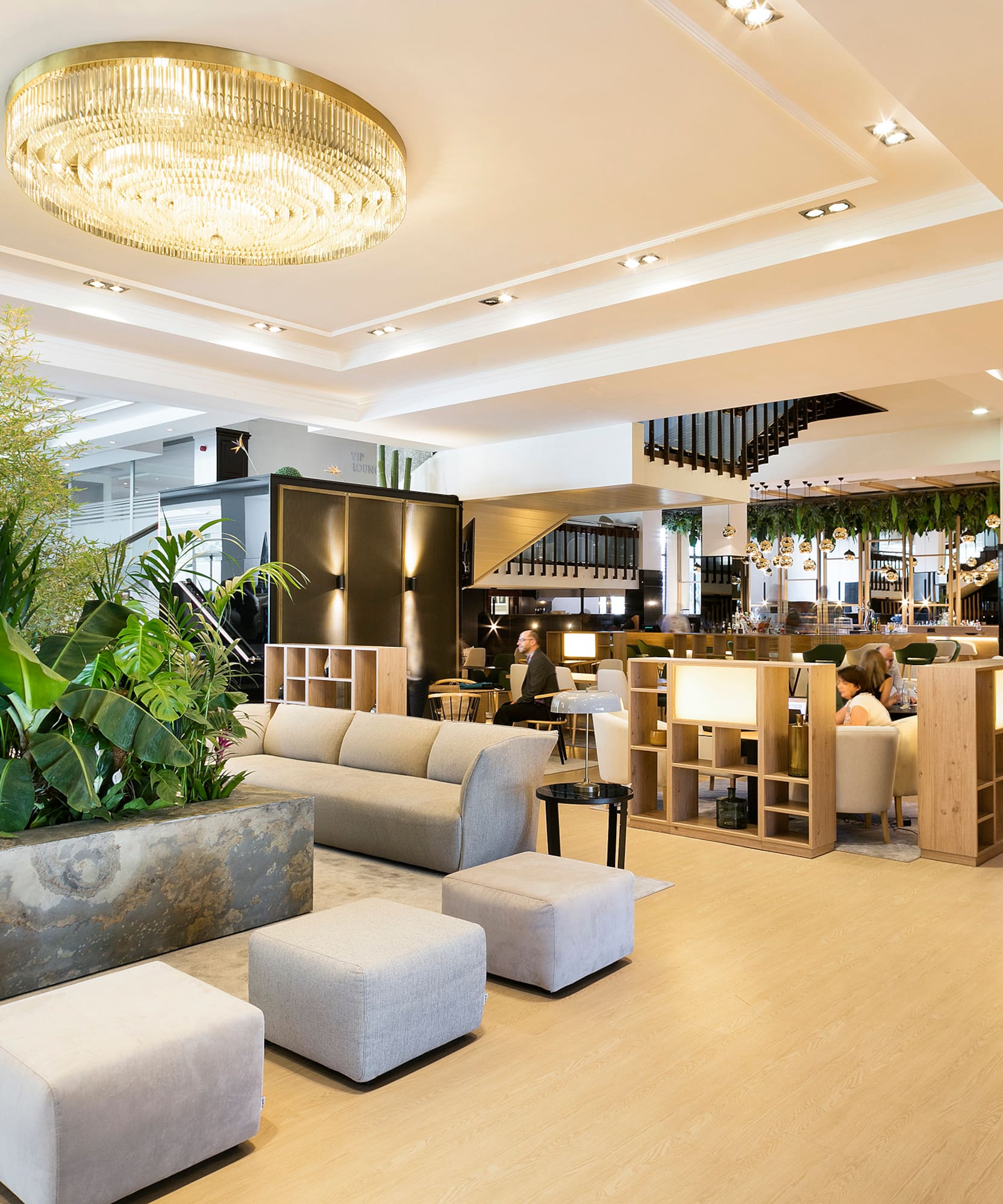 Luxurious hotel lounge with lush plants, modern sofas, and gold chandelier.